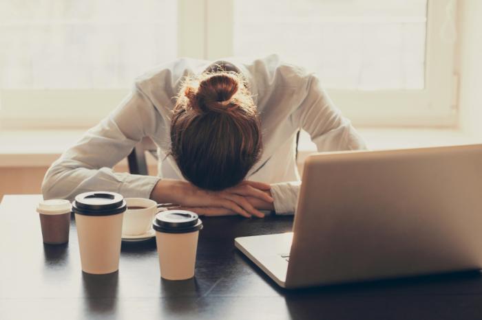 sleepy-office-worker-at-desk-with-multiple-coffees